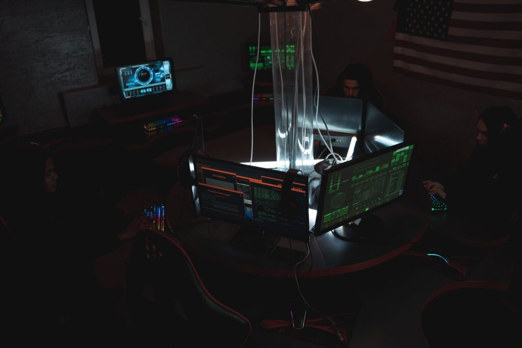 Team of cybersecurity experts collaboratively working on data protection in a dimly lit room filled with computers.