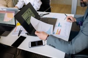 Professionals analyzing charts and graphs on laptops during a business meeting.